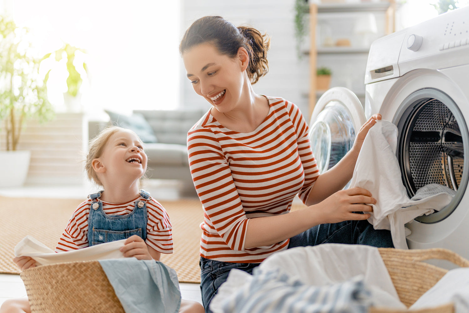 A mother and daughter happily doing laundry together